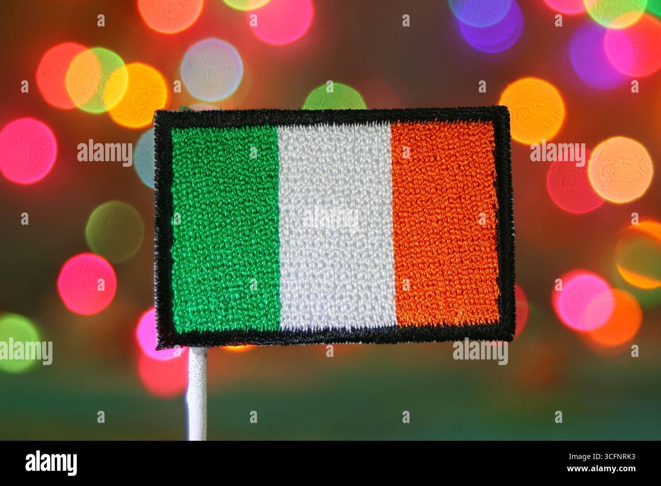 Stickaufnäher mit irischer Flagge und festlichem Hintergrund im Regenbogenbogenbokeh, ideal für Feiertage, Weihnachten, Neujahr und Nationalfeierlichkeiten. Stockfoto