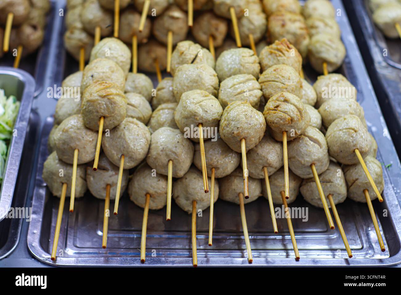 Thailändische gegrillte Schweinefleischspieße auf rostfreiem Tablett, ikonisches Street Food Thailands, beliebt auf Nachtmärkten und kulinarischem Tourismus. Stockfoto