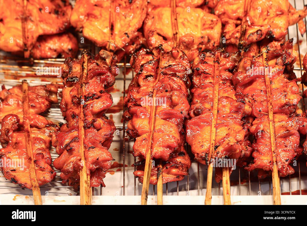 Gegrillte Hühnerknochen mit süßer roter Sauce, legendäre thailändische Straßengerichte, die oft auf geschäftigen Nachtmärkten zu finden sind. Stockfoto