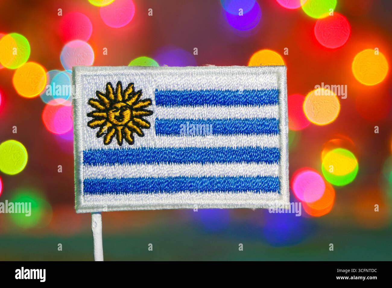 Gestickte Uruguay-Flagge auf lebendigem Bokeh-Hintergrund, Symbol für Unabhängigkeit, Nationalstolz, Feiertag und festliche Neujahrsfeier. Stockfoto
