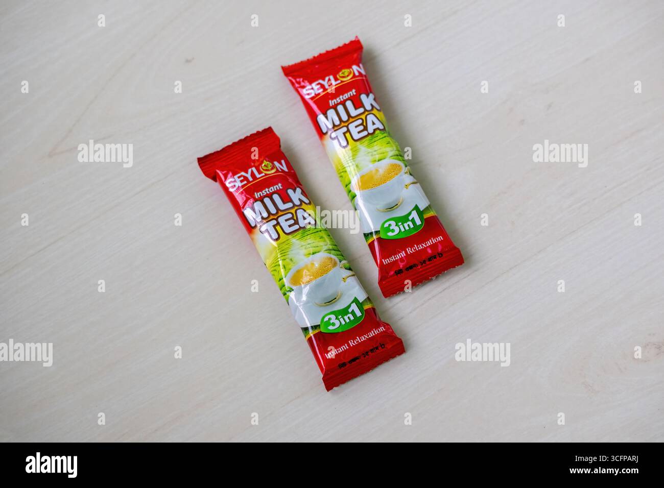Zwei SEYLON 3-in-1 Instant Milk Tea-Pakete auf Holz symbolisieren schnelle Entspannung und eine gemütliche Pause. Stockfoto