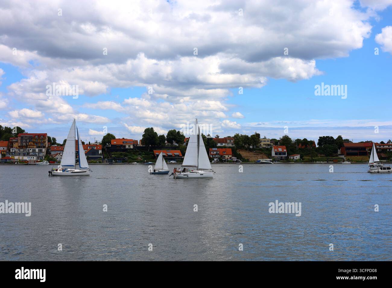 Segelboote auf dem See Mikołajskie mit der Stadt Mikołajki im Hintergrund. Blick vom Boot Stockfoto