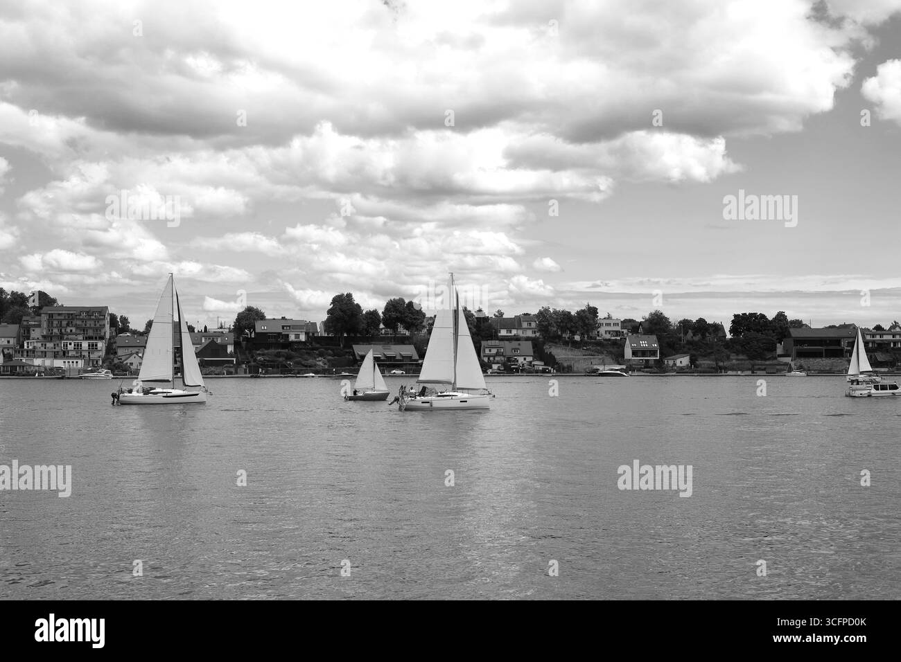 Schwarz-weiß-Bild von Segelbooten auf dem See Mikołajskie mit der Stadt Mikołajki im Hintergrund Stockfoto