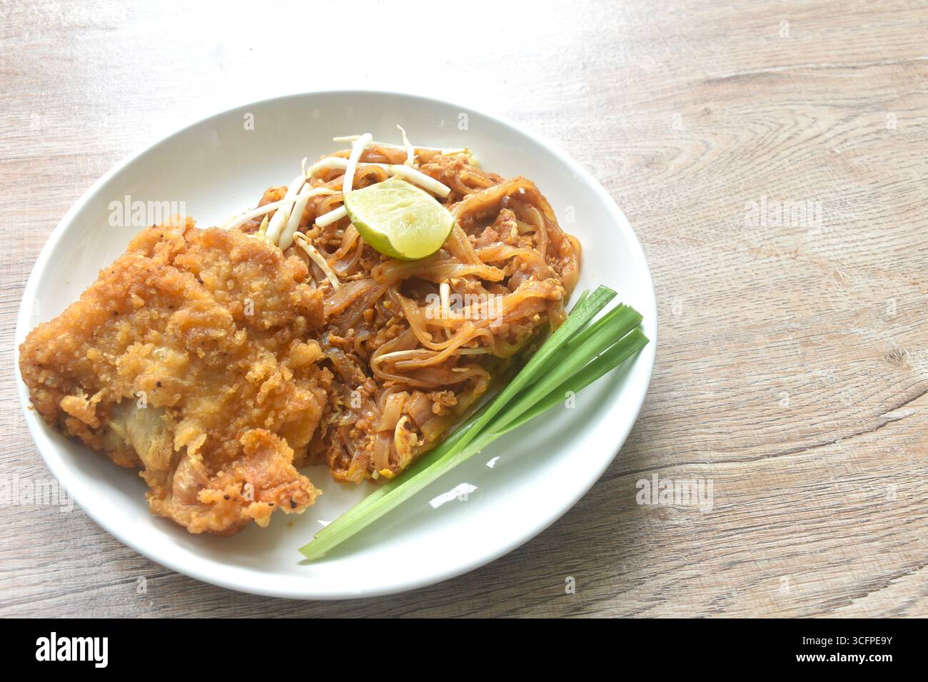 Gebratene Reisnudeln mit trockenen Garnelen und Ei-Belag mit knusprigem gebratenem Huhn auf Teller auflegen Stockfoto