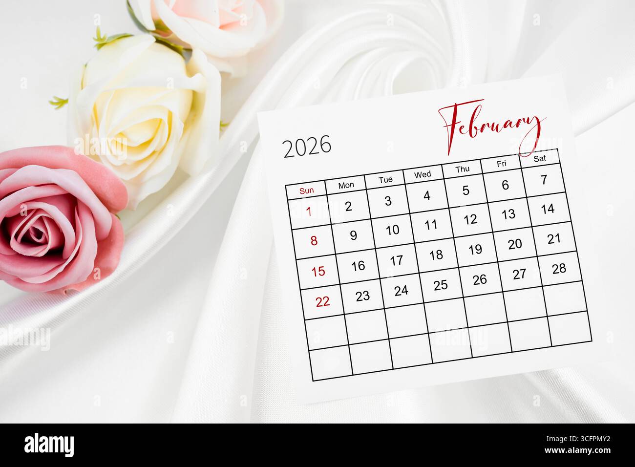 Kalenderseite Februar 2026 und Rosenblume auf Satin-Textil-Hintergrund. Stockfoto