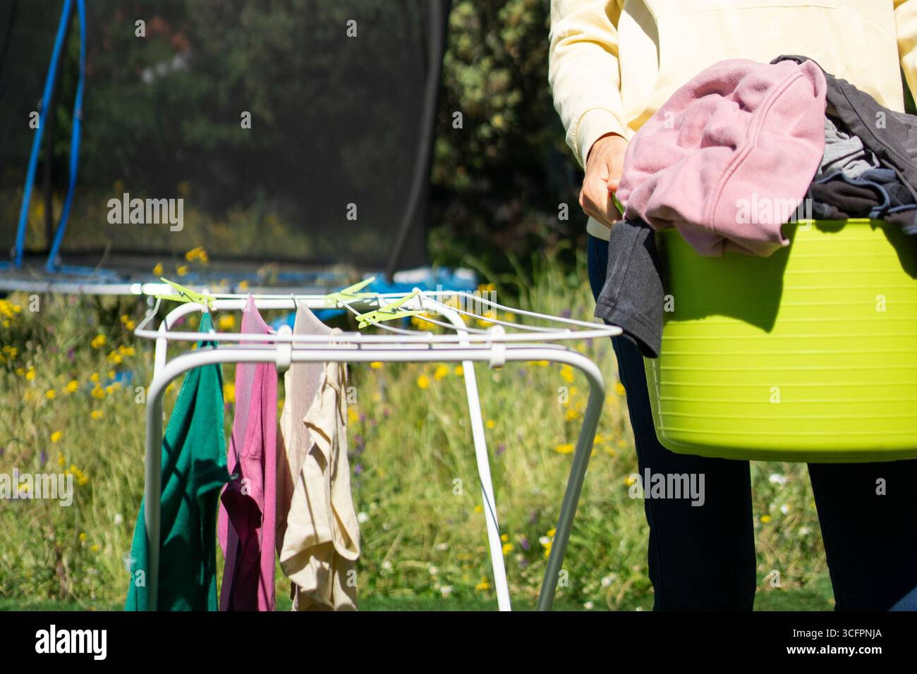 Hausfrau hängte nasse Kleidung an der Wäscheleine im Garten an sonnigen Tagen Stockfoto