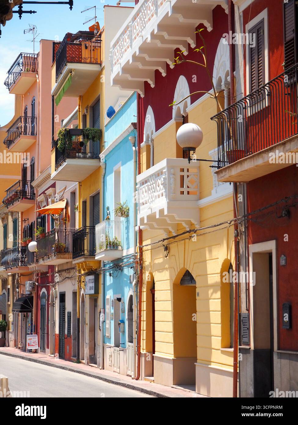 Farbenfrohe mediterrane Straße in Giardini Naxos in der Nähe von Taormina mit lebhaften Fassaden, Balkonen und traditioneller sizilianischer Architektur Stockfoto
