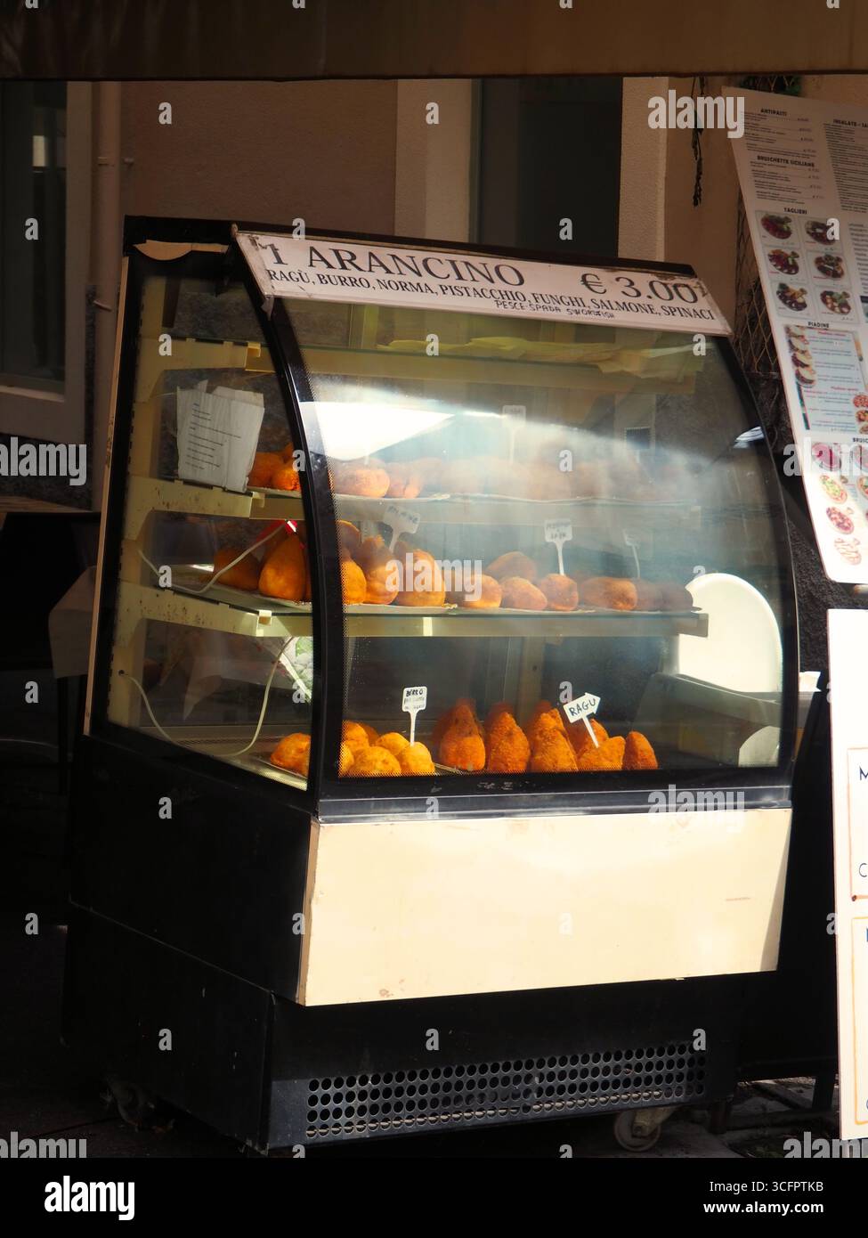 Arancino-Ausstellung in Taormina Sizilien mit traditionellem italienischem Streetfood in Glasvitrine im lokalen Geschäft Stockfoto