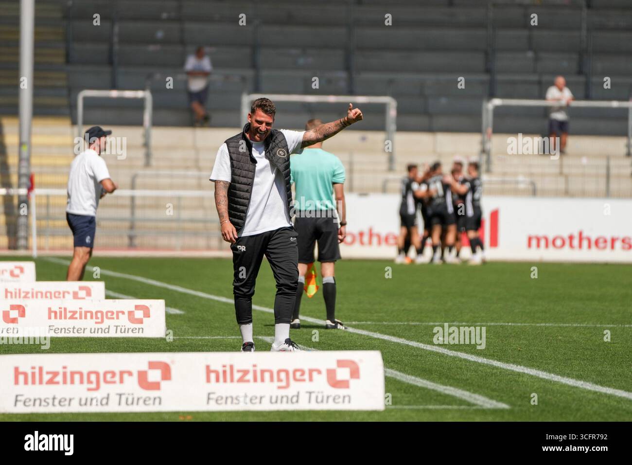 Freiburg Im Breisgau, Deutschland. August 2025. Pascal Reinhardt (SG Sonnenhof Gro?aspach, Trainer) nach dem 0:1 der mit Daumen hoch in Richtung Maximilian Reule (SG Sonnenhof Gro?aspach, 1) zeigt und sich freut und im Hintergrund sieht man die Mannschaft bei Torjubel Regionalliga S?dwest, SC Freiburg U23 vs SG Sonnenhof Gro?aspach, Dreisamtstadion, 24.08.2025 DFB/DFL-VORSCHRIFTEN VERBIETEN JEDE VERWENDUNG VON FOTOGRAFIEN ALS BILDSEQUENZEN und/Alamy News Stockfoto