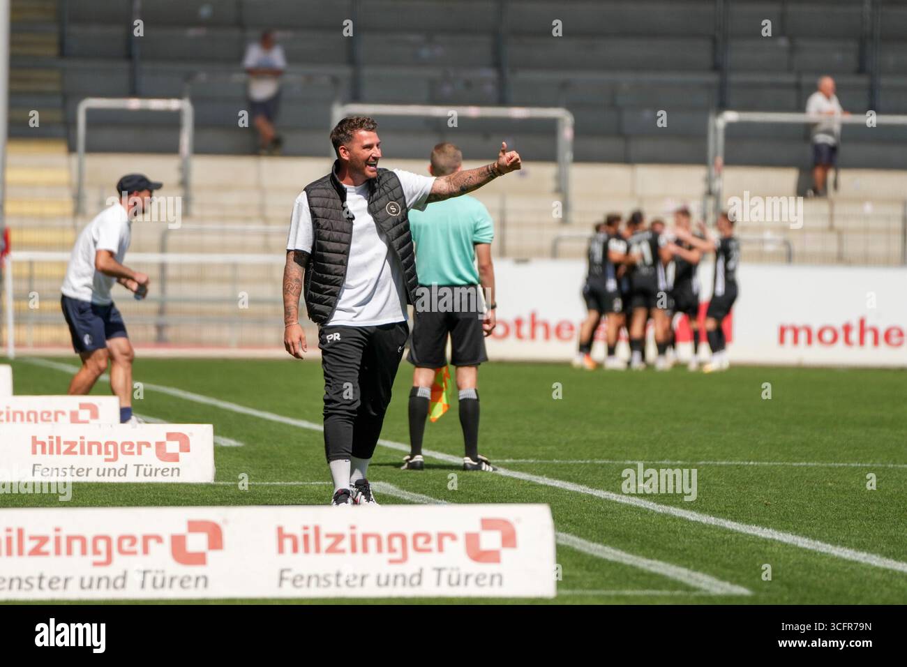 Freiburg Im Breisgau, Deutschland. August 2025. Pascal Reinhardt (SG Sonnenhof Gro?aspach, Trainer) nach dem 0:1 der mit Daumen hoch in Richtung Maximilian Reule (SG Sonnenhof Gro?aspach, 1) zeigt und sich freut und im Hintergrund sieht man die Mannschaft bei Torjubel Regionalliga S?dwest, SC Freiburg U23 vs SG Sonnenhof Gro?aspach, Dreisamtstadion, 24.08.2025 DFB/DFL-VORSCHRIFTEN VERBIETEN JEDE VERWENDUNG VON FOTOGRAFIEN ALS BILDSEQUENZEN und/Alamy News Stockfoto