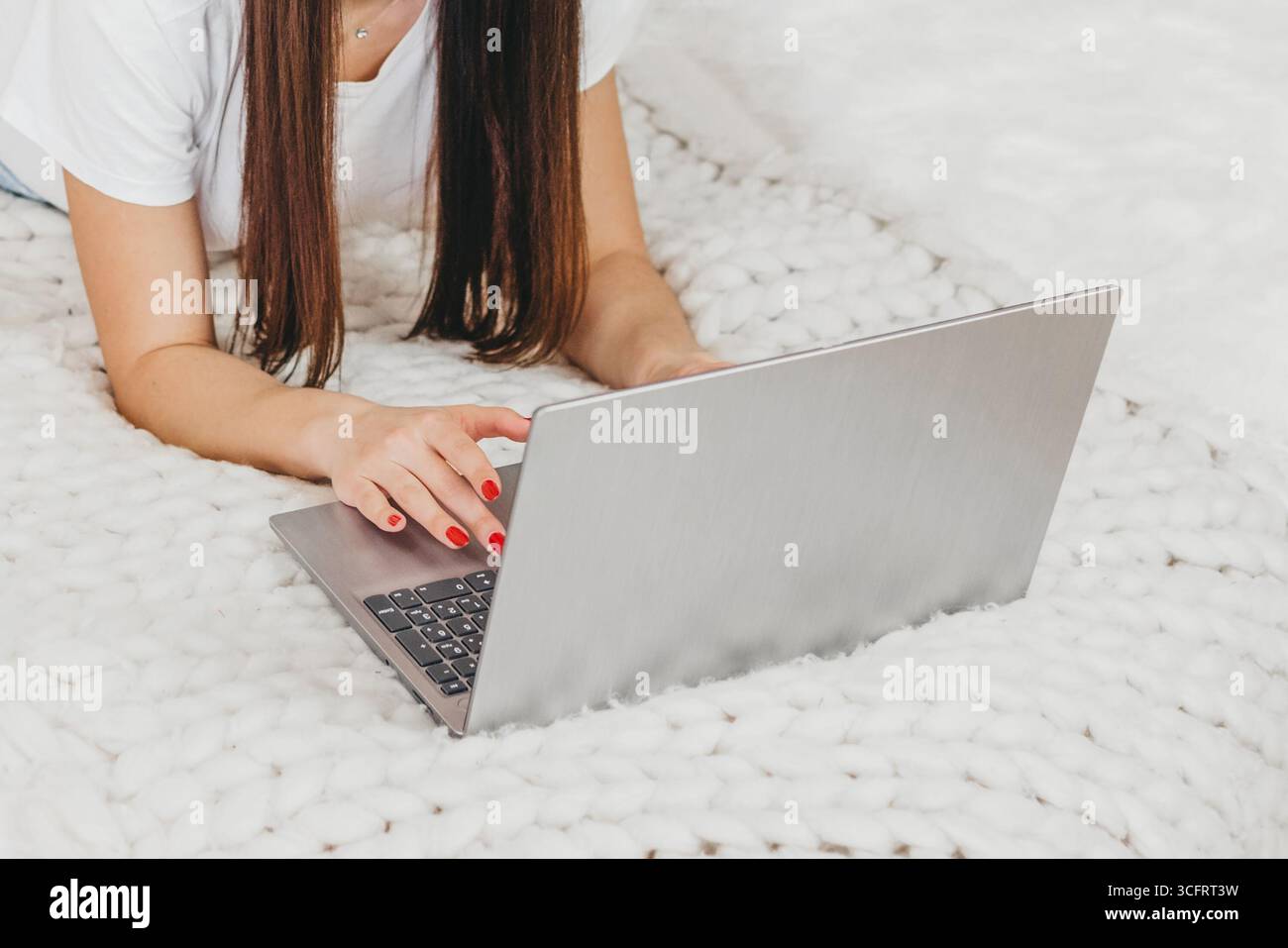Die Werbemanagerin für Mädchen arbeitet zu Hause mit einem Laptop, der auf einem weißen Bett von oben liegt. Moderner Beruf Stockfoto