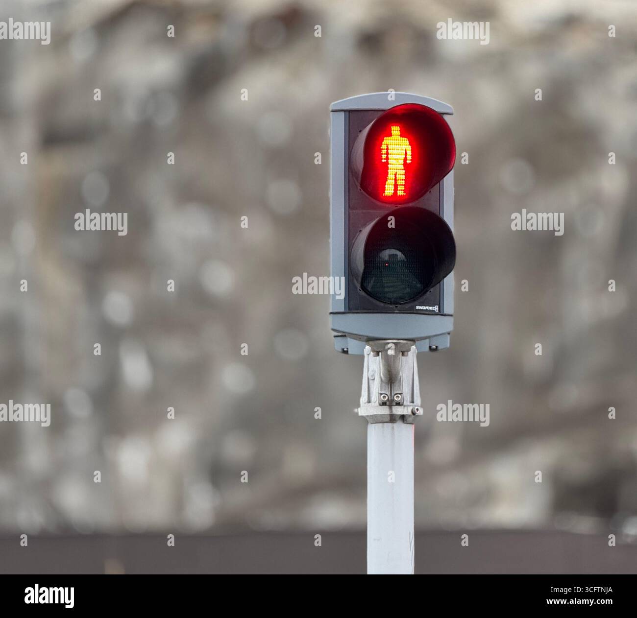 Rotes Fußgängerampelsignal zeigt eine stehende Figur, Nahaufnahme vor verschwommenem Hintergrund. - Smartphone-aufgenommenes Stockfoto