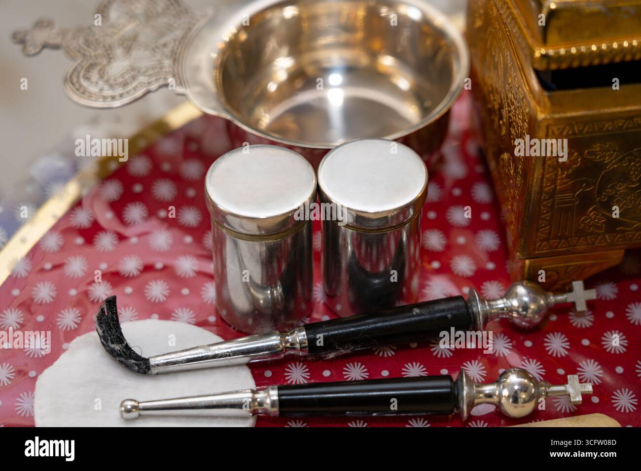 Nahaufnahme von liturgischen Metallgefäßen und Werkzeugen, die bei christlichen religiösen Zeremonien verwendet werden. Die Komposition besteht aus zwei silbernen Behältern, einem kleinen Meter Stockfoto