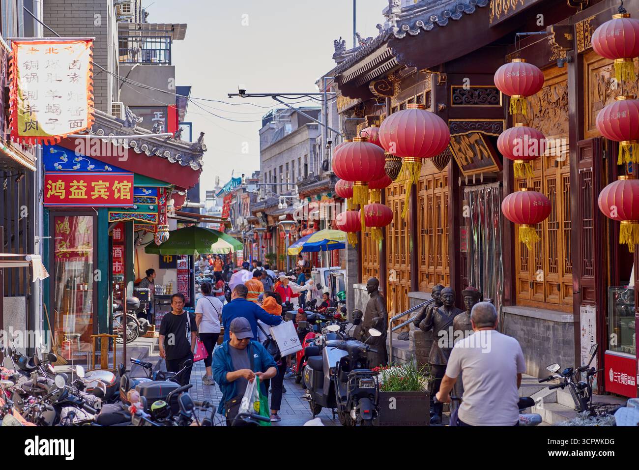 Geschäftige Hutong-Seitenstraße neben der Qianmen-Straße voller Menschen und Geschäfte Stockfoto