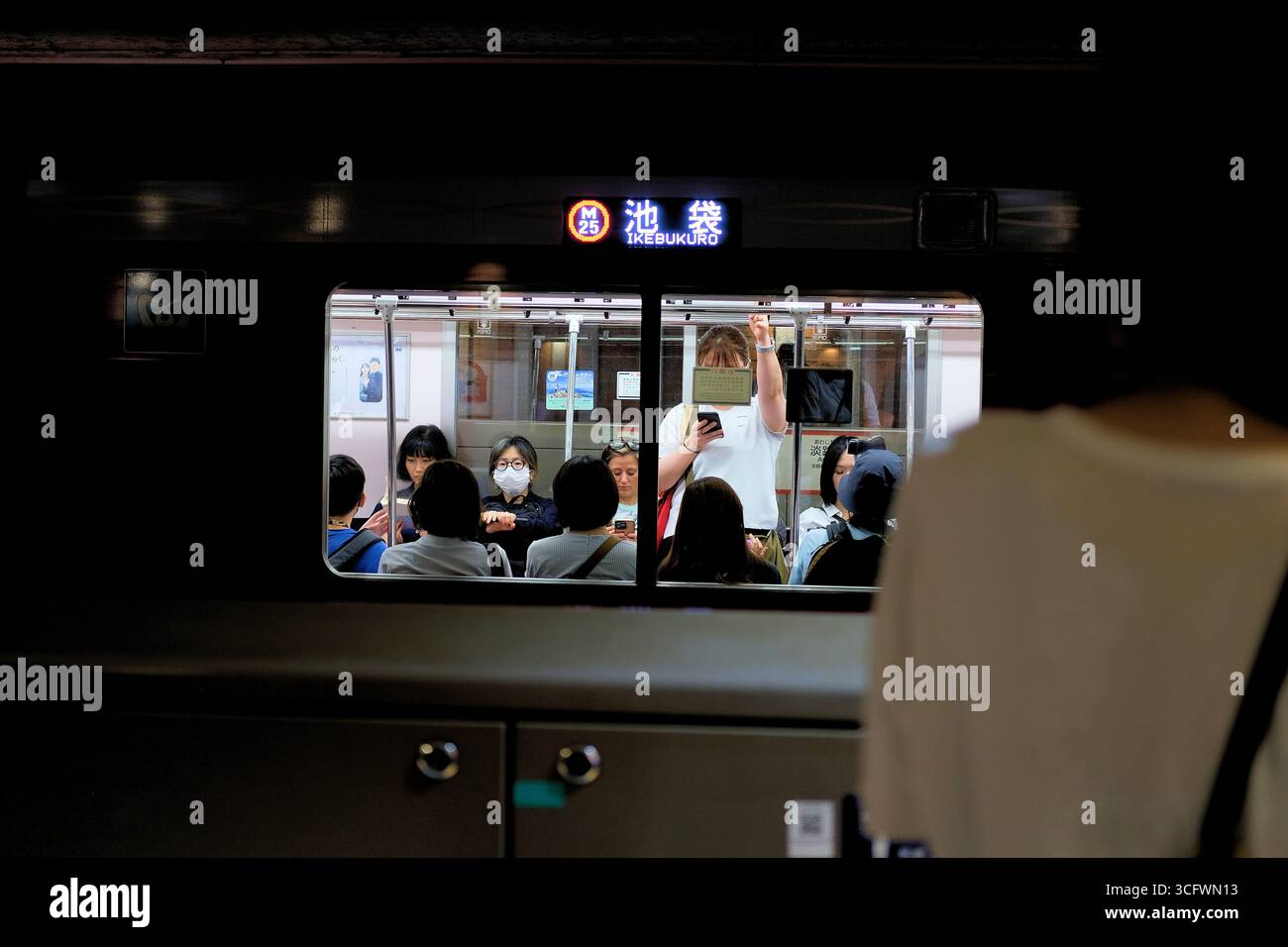 Passagiere in einem U-Bahn-Auto auf dem m25-Bahnsteig am Bahnhof Ikebukuro der Tokyo Metro Marunouchi Line; Tokio, Japan; U-Bahn-Benutzer und -Fahrer. Stockfoto