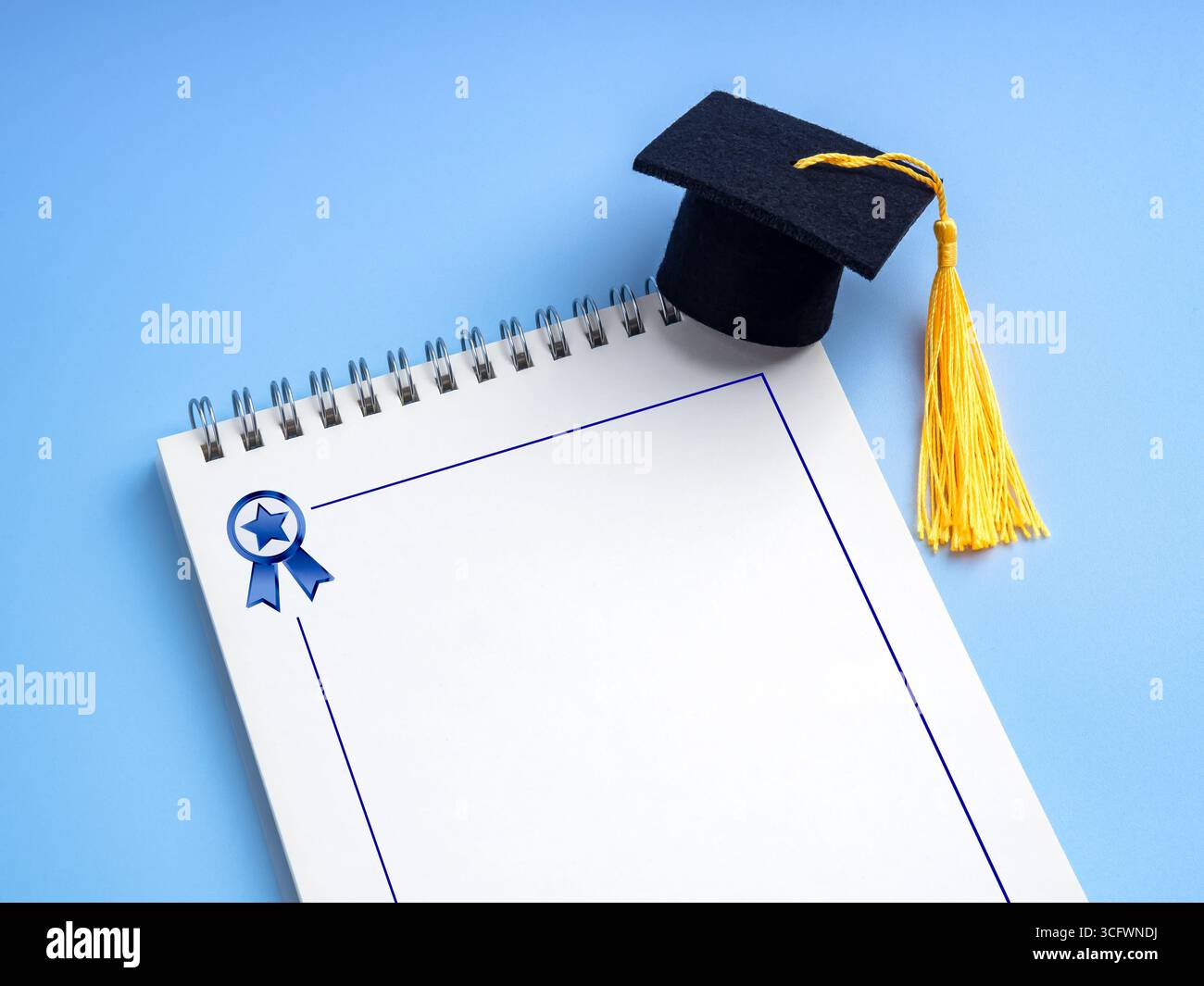 Abschlusskappe auf weißem, leerem Spiralnotizblock mit Preissymbol auf blauem Hintergrund, für Bildungsplanung, Schülerleistung, To-Do-Liste, Knoten Stockfoto