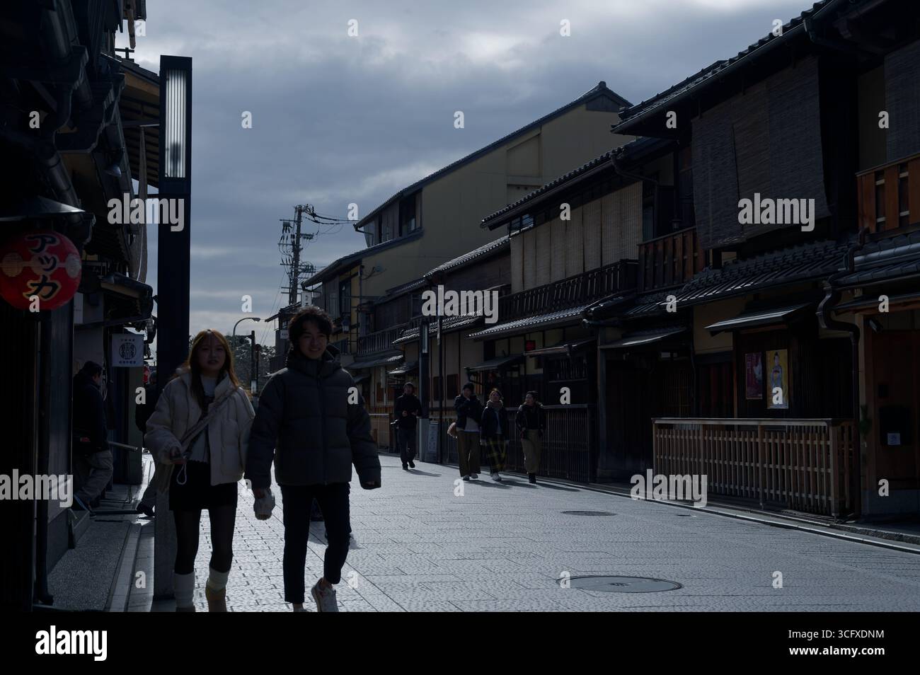 Ein Paar geht Hand in Hand entlang einer traditionellen Straße, eingerahmt von historischen Machiya-Häusern aus Holz Stockfoto