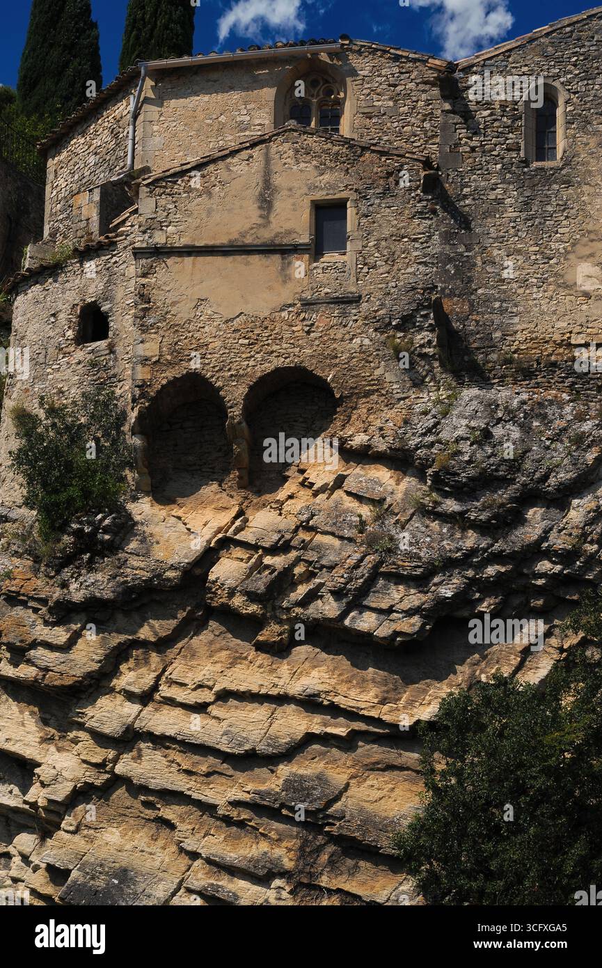Geschichtete oder geschichtete Sedimentgesteine stützen Steinschutt-Mauern, die seit gerendeten und bemalten wurden, der ehemaligen Kathedrale der Heiligen Maria von der Himmelfahrt aus dem 15. Jahrhundert, die über 40 m hohen Abgrund über dem Fluss Ouvèze in der römischen und mittelalterlichen Stadt Vaison-la-Romaine in Vaucluse, Provence-Alpes-Côte d’Azur, südöstlich Frankreichs thront. Die einzigartige Struktur dient heute als Kulturzentrum. Stockfoto