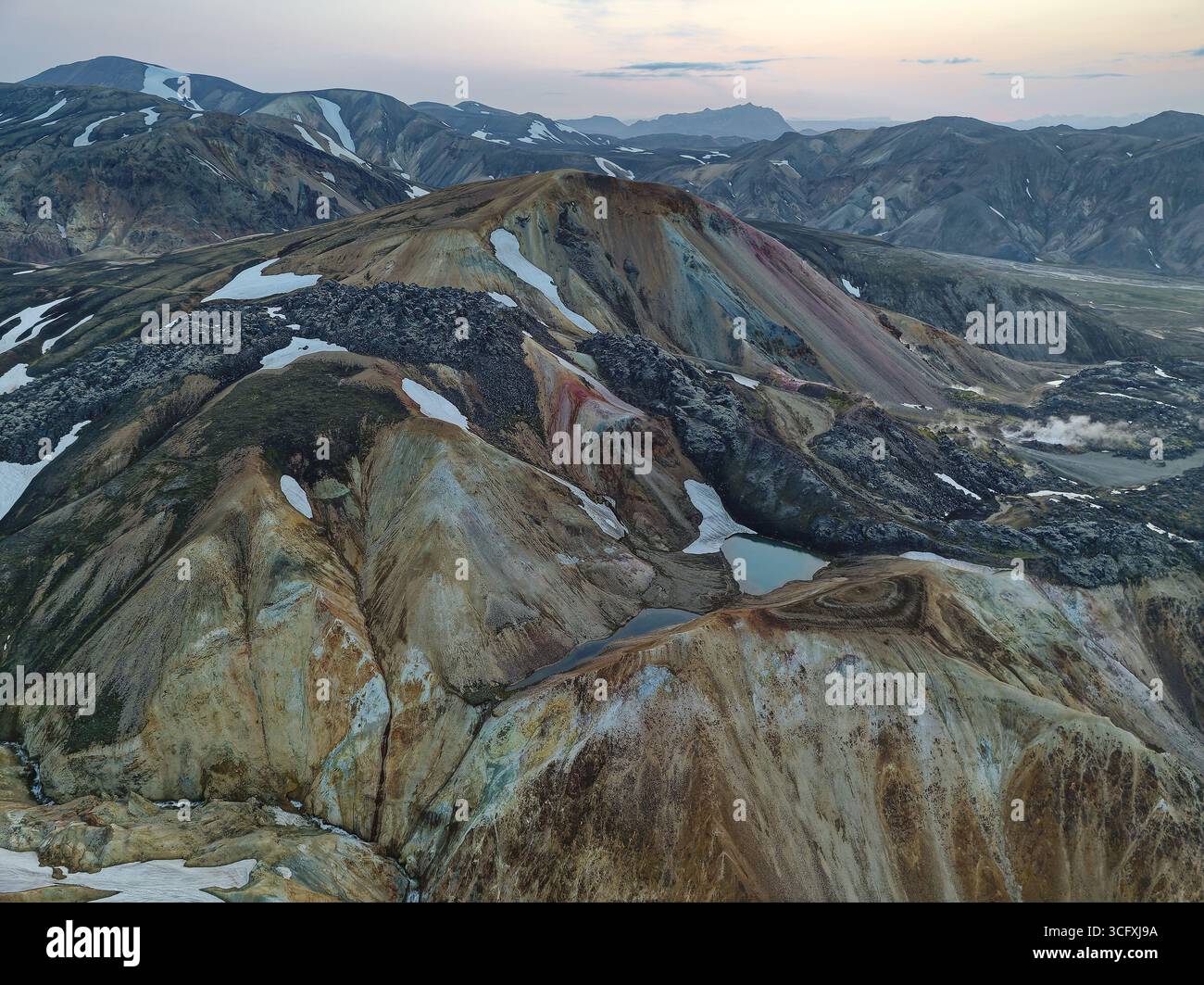 Aus der Vogelperspektive auf die beeindruckende Landschaft der Highlands, wo farbenfrohe Berge unter einem riesigen Himmel auf Gletscherreste treffen, was einen atemberaubenden blick auf IC schafft Stockfoto