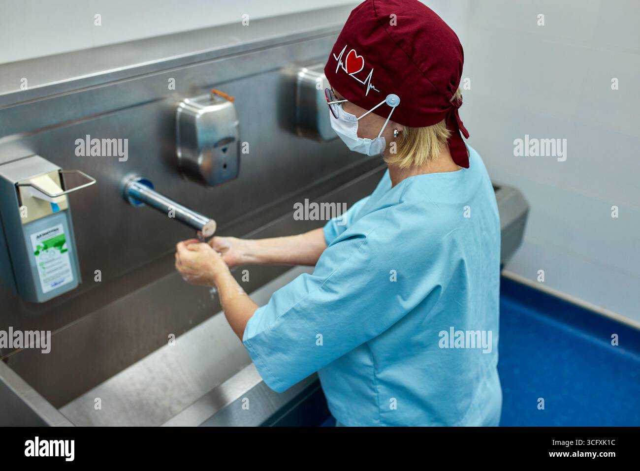 Ein medizinischer Mitarbeiter befolgt die richtigen Handwaschtechniken an einem Spital, um Hygiene zu gewährleisten und Infektionen zu verhindern. Uniform und Protektiv tragen Stockfoto