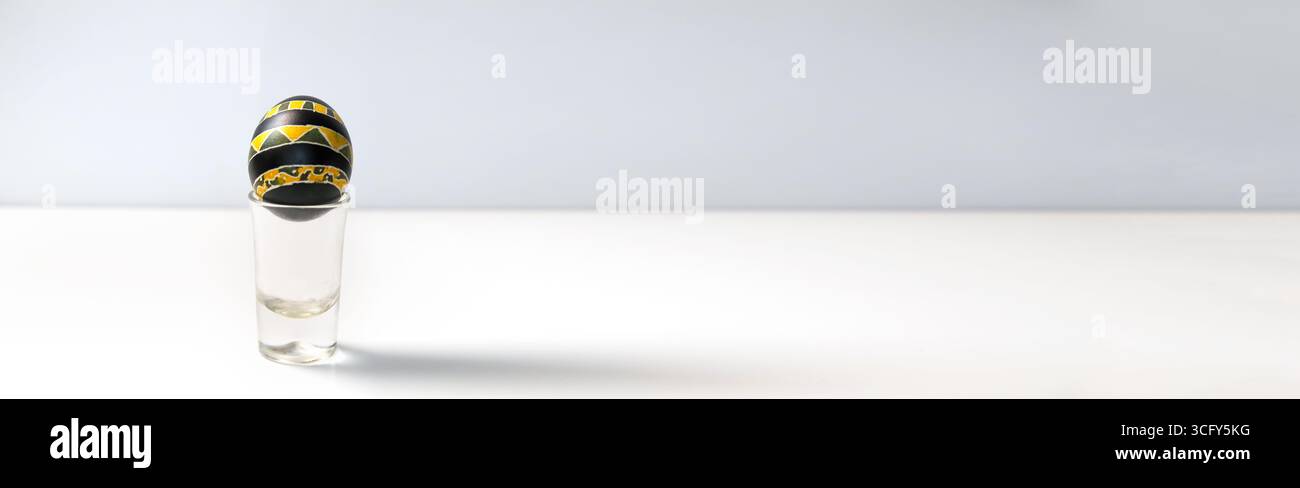 Banner mit einer traditionellen Pysanka, ukrainischem Osterei, vor einem sauberen weißen Hintergrund. Ukrainische Volkskunst Urlaubsvorlage. Schwarz-gelbes Easte Stockfoto