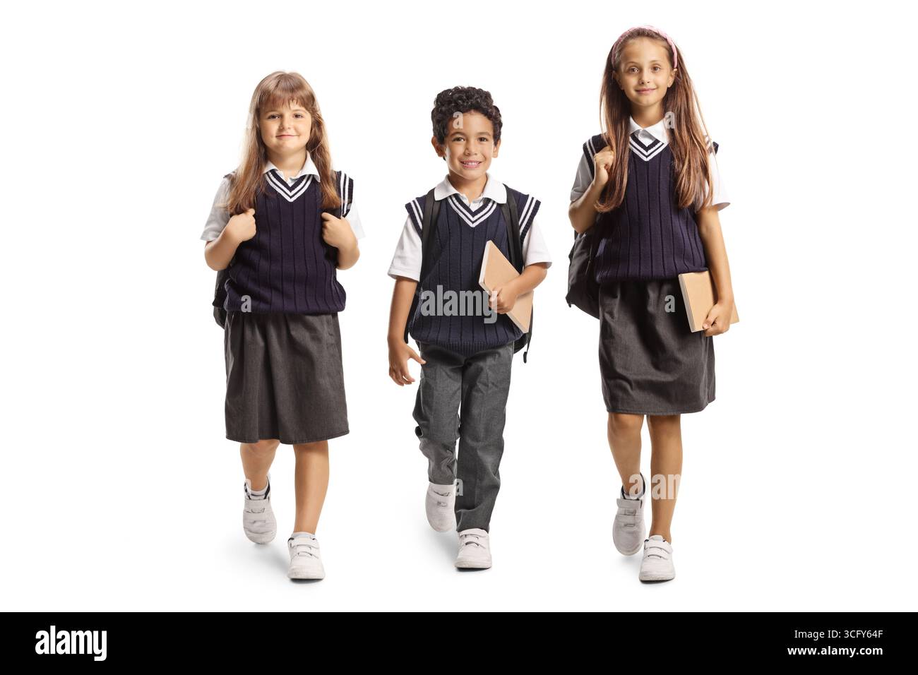 Kinder in Schuluniformen, die auf die Kamera zugehen, isoliert auf weißem Hintergrund Stockfoto