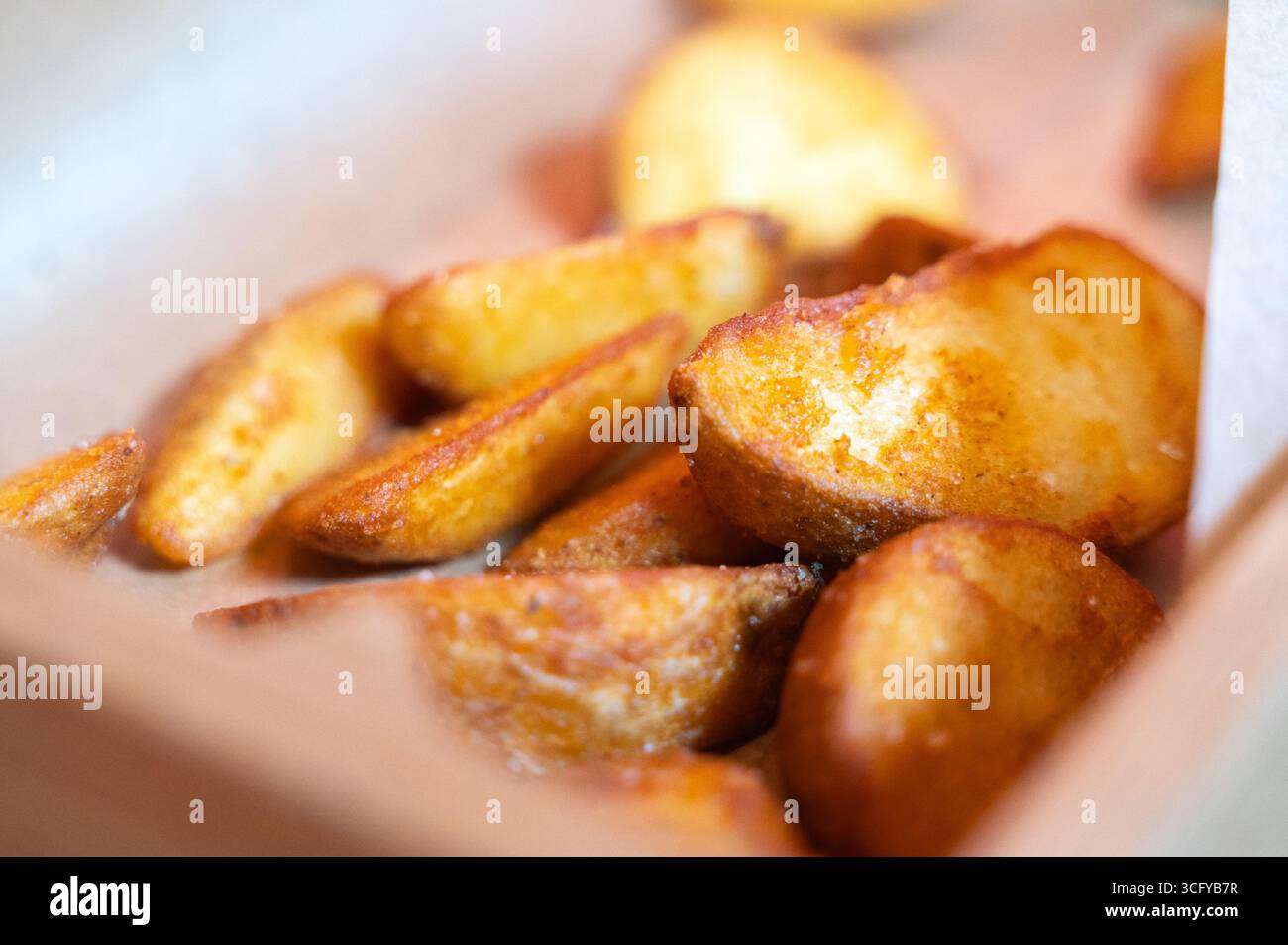 Köstlich goldene und knusprige Kartoffelscheiben, serviert in einer Fastfood-Box. Perfekt für Snacks oder Beilagen. Stockfoto