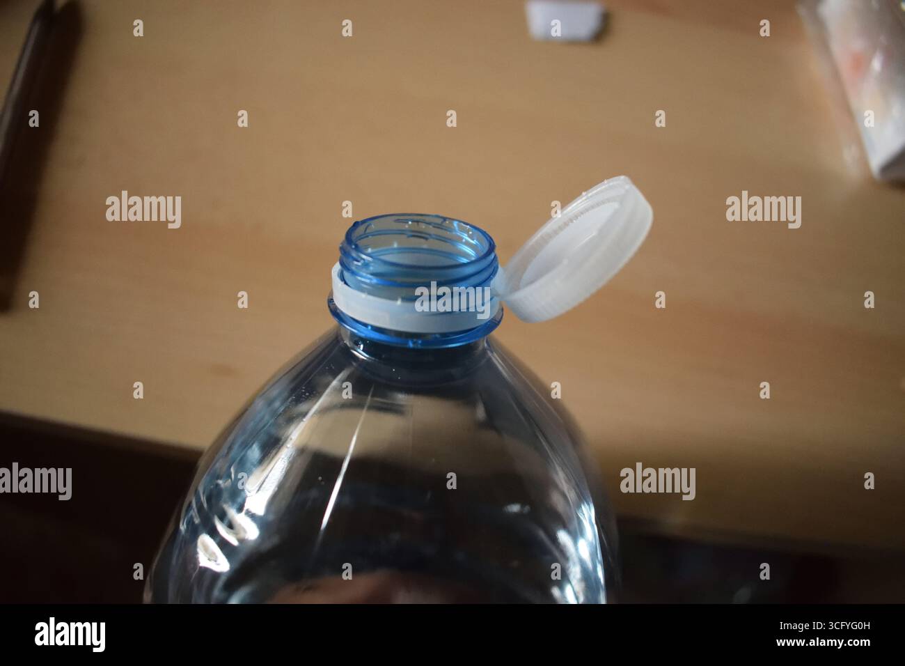 Nahaufnahme einer Plastikwasserflasche mit aufklappbarem weißem Verschluss und Gewindehals. Flaschendesign und Verschluss-Mechanismus im europäischen Design Stockfoto