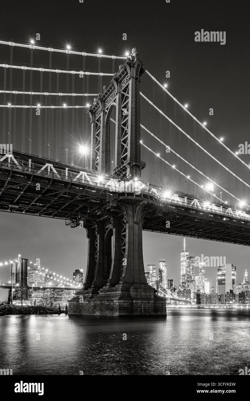 New York City Schwarzweiß-Nachtblick auf die Manhattan Bridge von DUMBO. Beleuchtete Skyline von Lower Manhattan mit Wolkenkratzern und East River Stockfoto