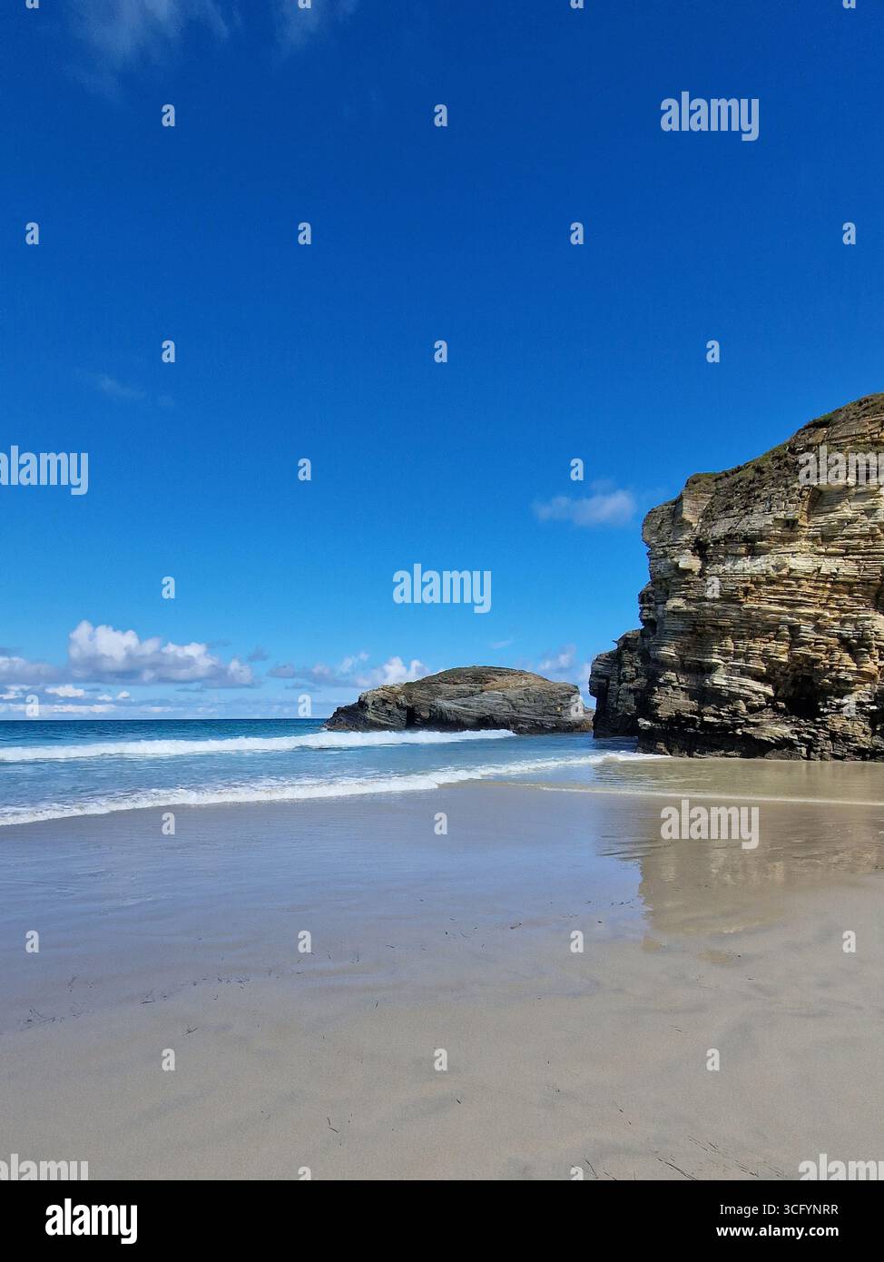 100. Wunderschöne Strandszene mit felsigen Klippen und ruhigen Wellen, unter einem hellblauen Himmel, die die Zuschauer einladen, die Ruhe der Natur und des Ko zu erleben Stockfoto