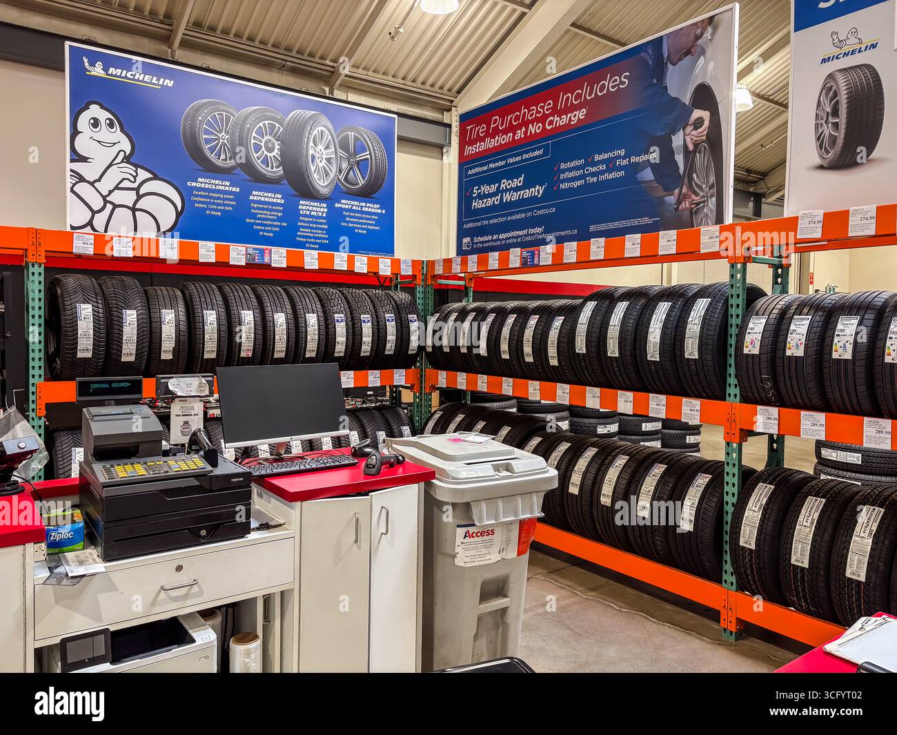 Costco-Reifenbereich mit Reifenreihen auf den Gepäckträgern, einem Serviceschalter und Werbeschildern von Michelin. Veranschaulicht den Kfz-Einzelhandel, Reifenverkauf, Stockfoto