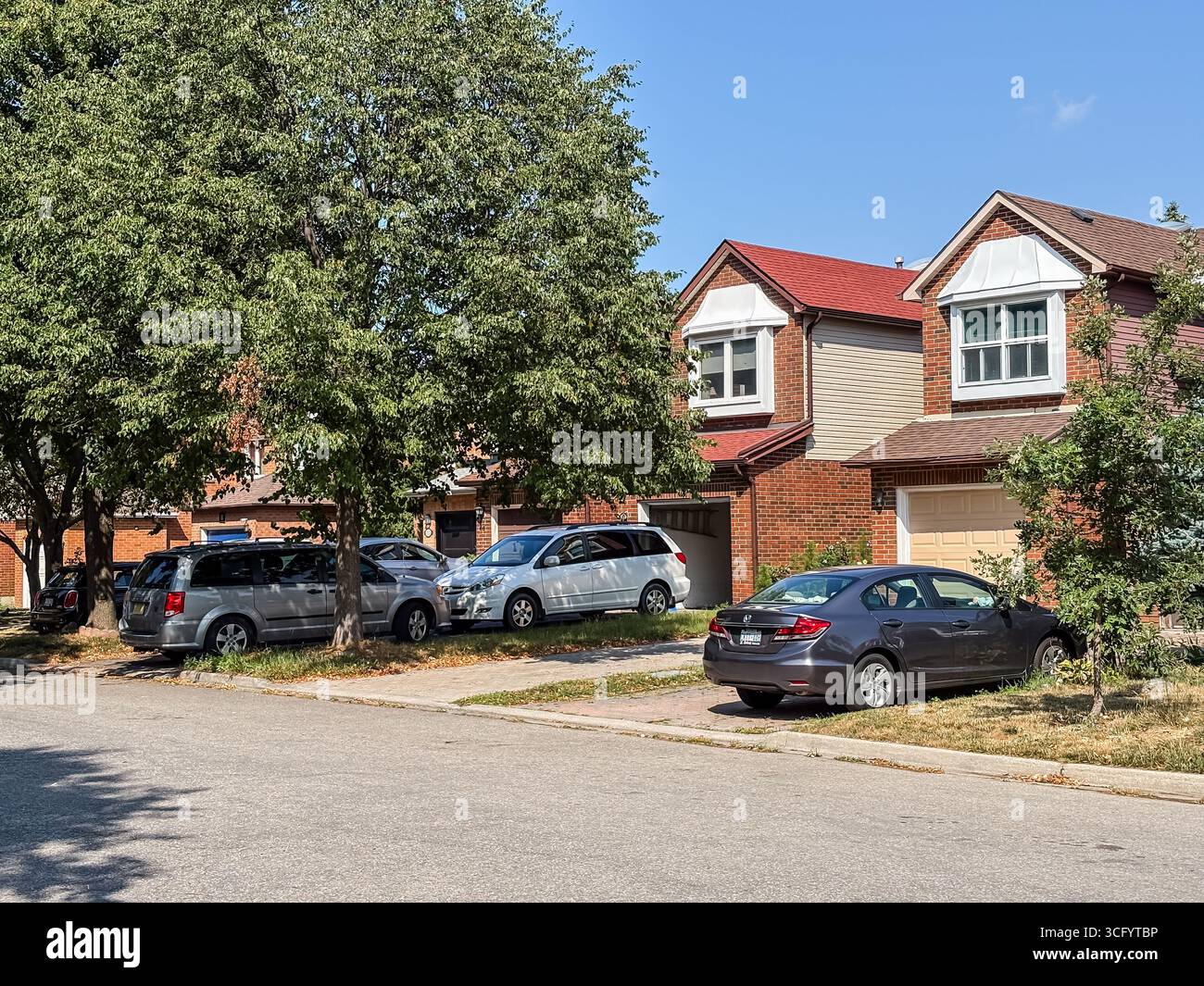 Die Straße im Viertel Toronto zeigt Häuser, geparkte Autos und alte Bäume an einem sonnigen Tag. Typisches Wohngebiet, das Ende der 1970er Jahre und Anfang der Jahre erbaut wurde Stockfoto