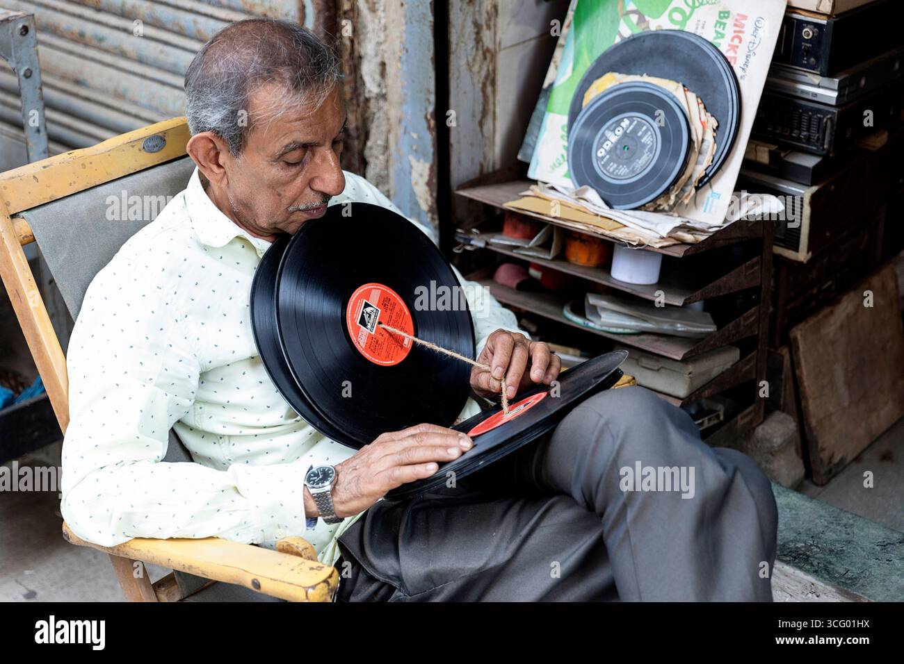 Interessante Szene aus Chor Bazaar, Antiquitätenläden in Mumbai in Indien, alter Mann, der sich seine Sammlung von LP-Schallplatten anschaut, Schallplatten zum Verkauf Stockfoto