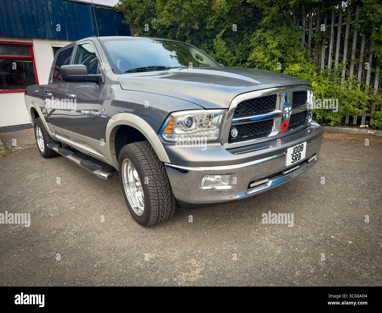 Ein silbergrauer Dodge RAM 1500 Crew Cab Pickup-Truck, der an klaren Tagen auf einer Asphaltoberfläche in der Nähe von Industriezäunen und Grünanlagen geparkt ist Stockfoto