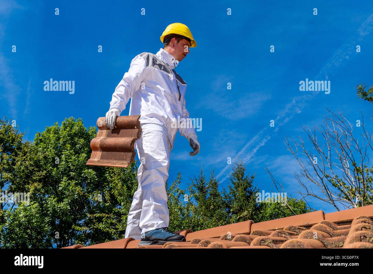 Bayern, Deutschland - 25. August 2025: Ein Dachdecker arbeitet auf einem Dach mit Fliesen. Ein klassischer Fachbetrieb, der Präzision, Sicherheit und körperliche Stärke zu einem traditionellen, unverzichtbaren Beruf kombiniert. *** Ein Dachdecker bei der Arbeit auf dem Dach mit Ziegeln. Klassischer Handwerksberuf, der Präzision, Sicherheit und körperliche Stärke vereint ein traditioneller, unverzichtbarer Beruf. Stockfoto