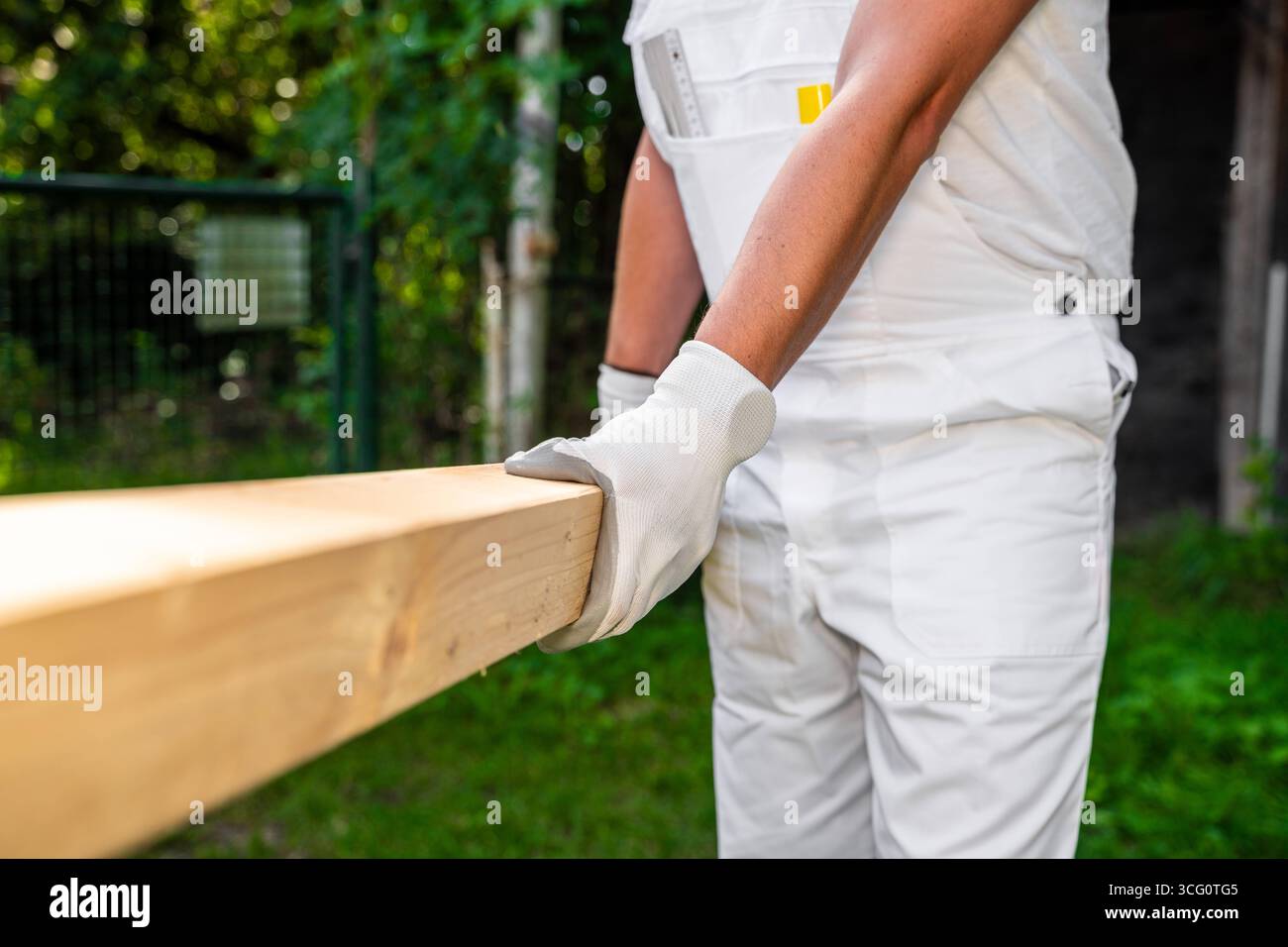 Bayern, Deutschland - 25. August 2025: Ein Zimmermann trägt einen Holzbalken auf einer Baustelle. Symbolbild der körperlichen Arbeit und der Verwendung von Holz als Naturbaustoff in der Bauindustrie *** ein Zimmermann trägt auf einer Baustelle einen Holzbalken. Symbolbild körperliche Arbeit und den Einsatz von Holz als natürlicher Baustoff im Baugewerbe Stockfoto