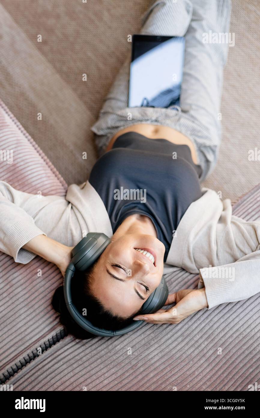 Frau, die sich zu Hause entspannt, Musik nach der Arbeit genießt. Stockfoto
