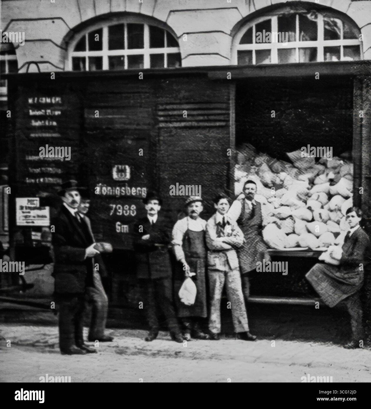 Foto aus L’Illustration, 24. Juni 1916, mit Waggons, die in Bern mit Brot beladen werden, um sie zu französischen Kriegsgefangenen zu transportieren. Diese humanitären Transporte wurden im Rahmen internationaler Abkommen organisiert, um die Versorgung der gefangenen Soldaten zu gewährleisten. Das Bild veranschaulicht die Logistik der Kriegshilfe und unterstreicht die Rolle der neutralen Schweiz bei der Vermittlung von Hilfe während des Ersten Weltkriegs. Stockfoto