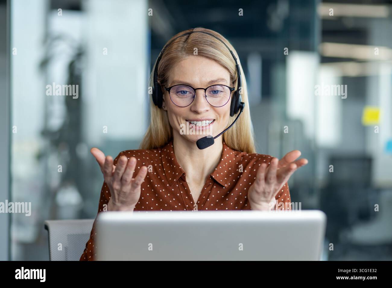 Selbstbewusste Geschäftsfrau mit Brille und Headset nimmt an einem Videoanruf Teil, was die Zusammenarbeit und effektive Kommunikation innerhalb eines veranschaulicht Stockfoto