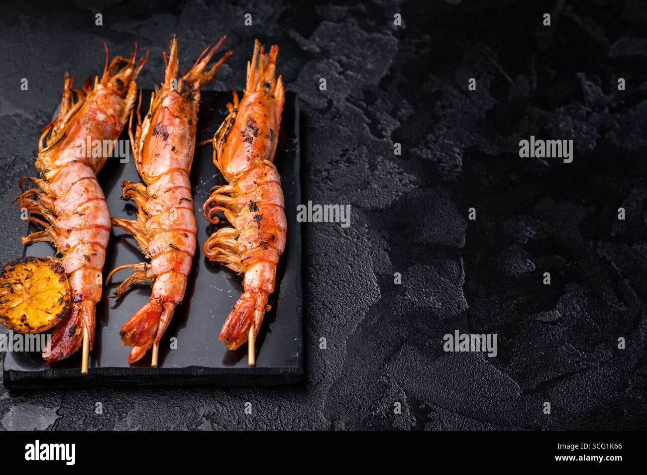 Garnelenkebab, Spieße mit gegrillten roten Garnelen Langostino Austral. Schwarzer Hintergrund. Draufsicht. Stockfoto