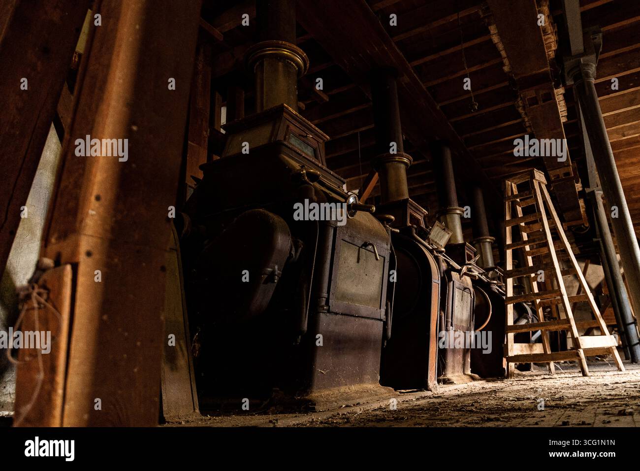 Alte Industrieanlagen in einem schwach beleuchteten Raum mit Holzleiter Stockfoto