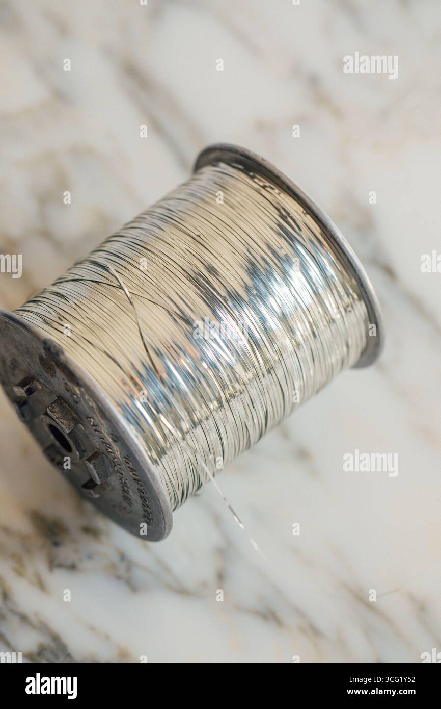 Silberfarbenes Metallgarn auf Spule Stockfoto