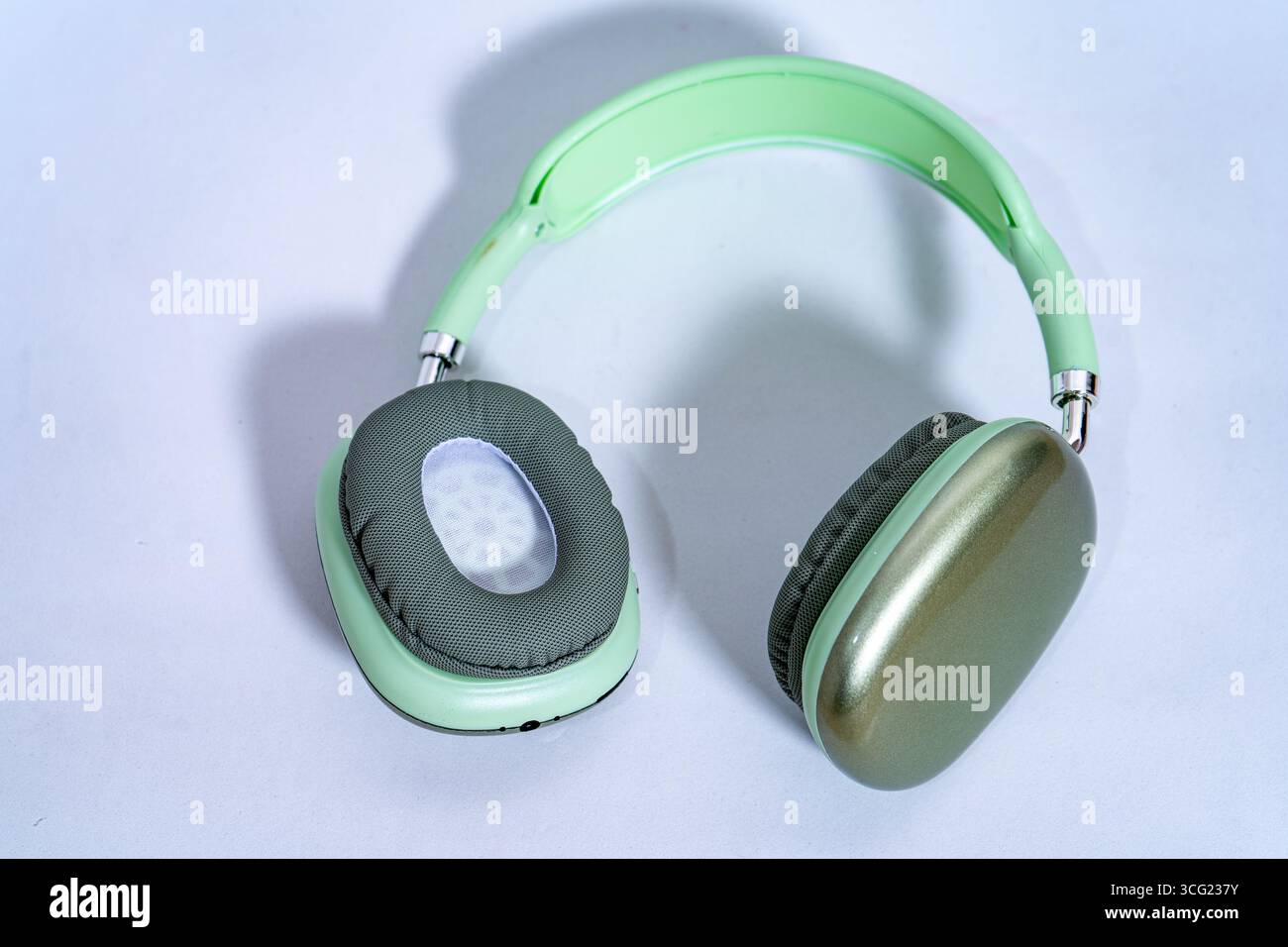 Stilvolle, kabellose Kopfhörer in Pastellgrün auf weißem Hintergrund, die moderne Audiotechnologie bieten Stockfoto