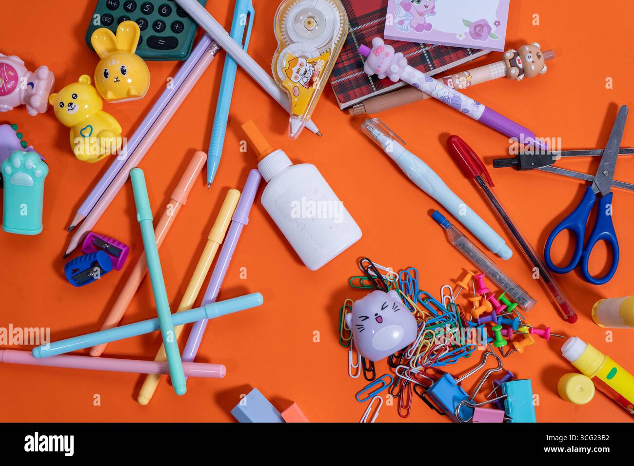 Farbenfrohe Schulutensilien auf leuchtendem orangefarbenem Hintergrund für die Schulzeit Stockfoto