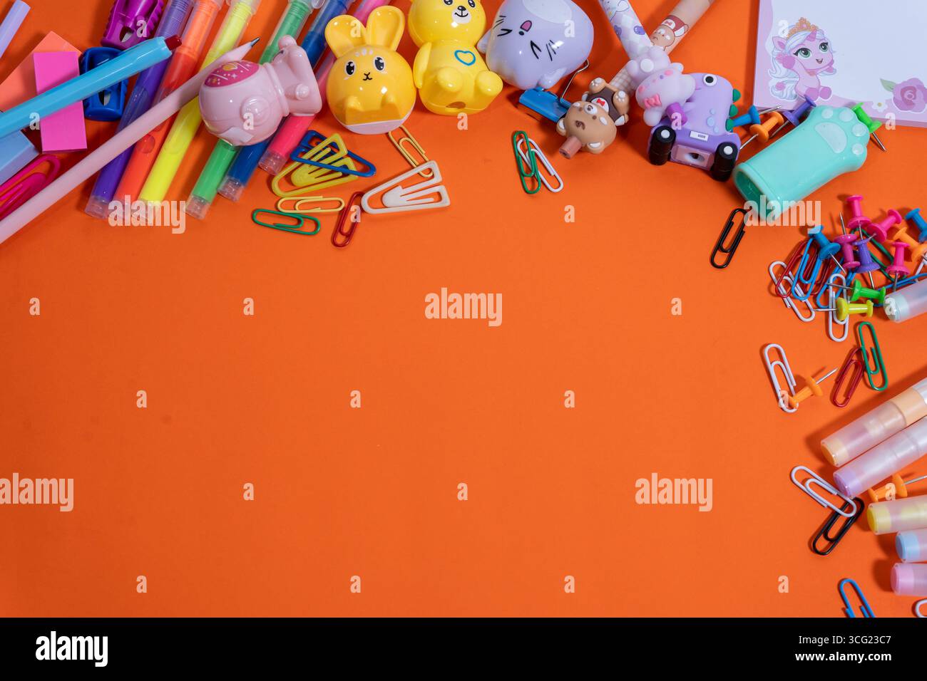 Back-to-School-Konzept mit farbenfrohen Schreibwaren vor einem leuchtenden orangefarbenen Hintergrund, die Raum für Text- oder Designelemente schaffen Stockfoto
