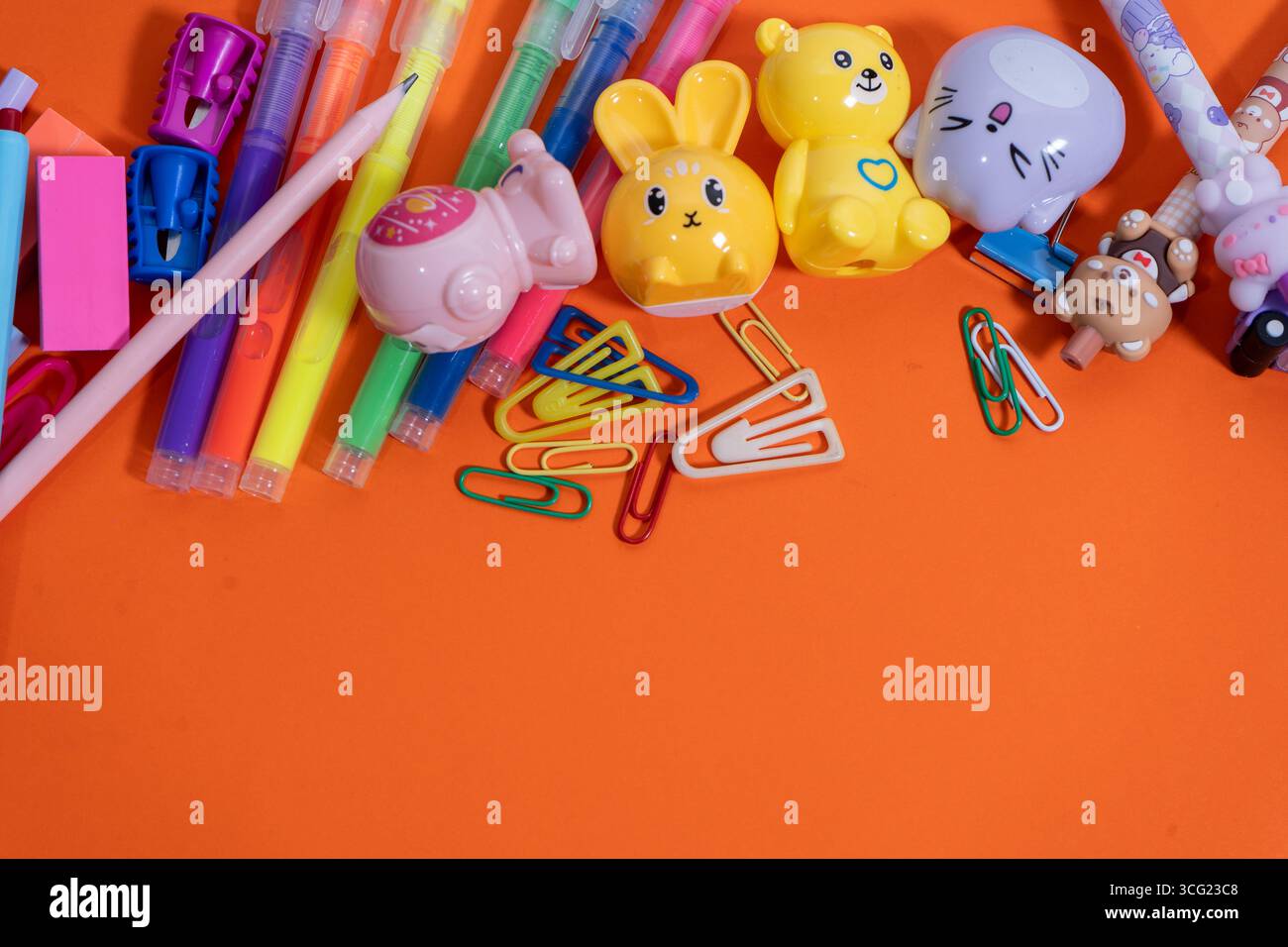 Back-to-School-Konzept mit farbenfrohen Schreibwaren, die eine Grenze auf einer orangefarbenen Oberfläche bilden Stockfoto