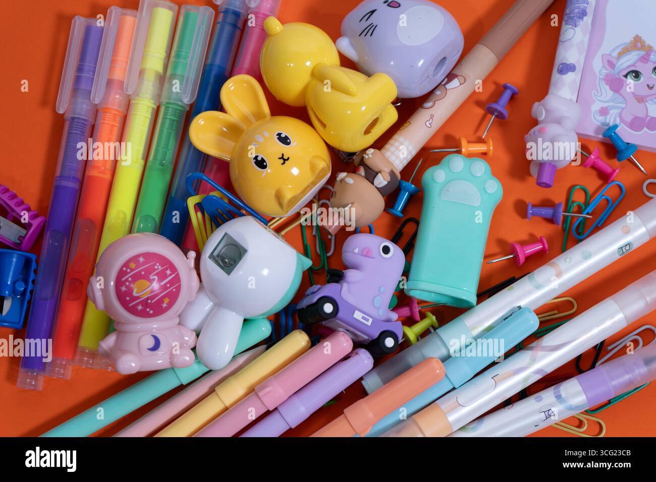 Pastellfarbene Kawaii-Schreibwaren sorgen für eine lebendige Wohnung für den Schulanfang auf orangem Hintergrund Stockfoto