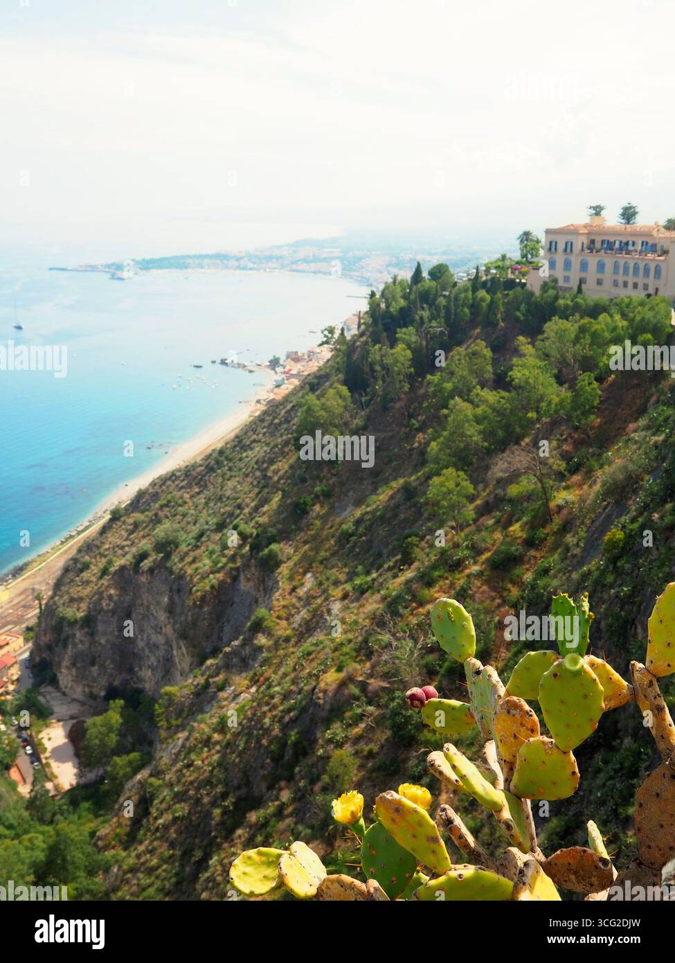 Blick auf Taormina an den Klippen mit mediterraner Küste, Kaktuspflanzen im Vordergrund und Küstenlandschaft entlang des Ionischen Meeres in Sizilien Stockfoto