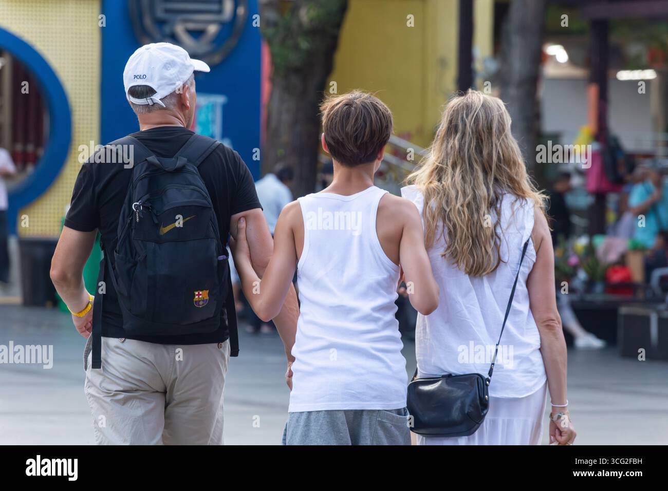 Rückansicht kaukasische Familie, Sohn, der seinen Vater und seine Mutter im Arm hält, während der Tour durch Singapur. Sie erkunden in Chinatown. Stockfoto Rückansicht kaukasische Familie, Sohn, der seinen Vater und seine Mutter im Arm hält, während der Tour durch Singapur. Sie erkunden in Chinatown. Stockfoto