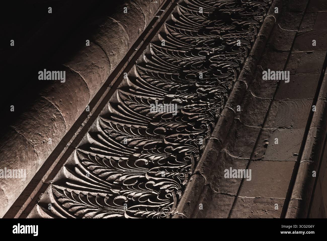 Nahaufnahme der wunderschönen, detaillierten architektonischen Schnitzereien an einer Wand unter dramatischer Beleuchtung, die Textur und Komplexität betonen Stockfoto